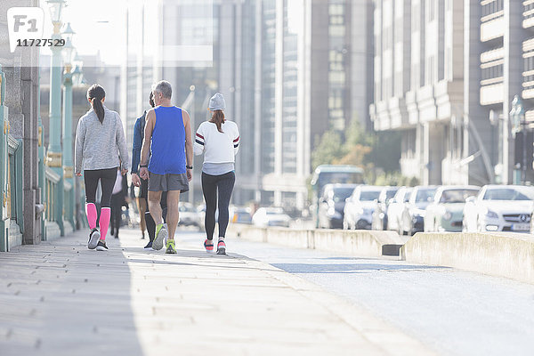 Läufer,  die auf dem sonnigen städtischen Bürgersteig laufen
