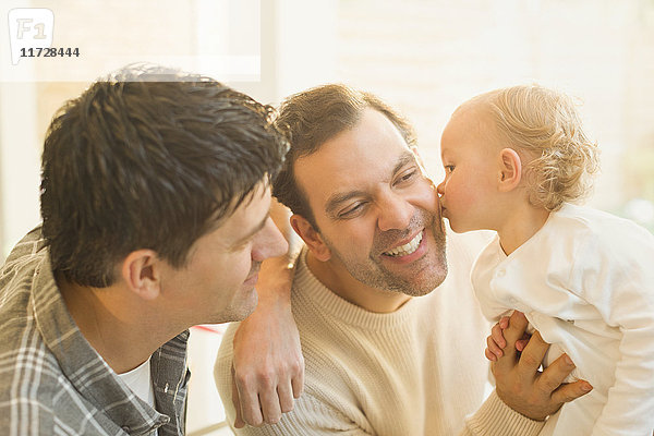 Zärtlicher Baby-Sohn,  der männliche schwule Eltern küsst.
