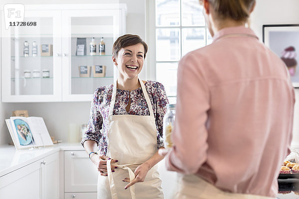 Lächelnde Catererinnen binden Schürzen in der Küche