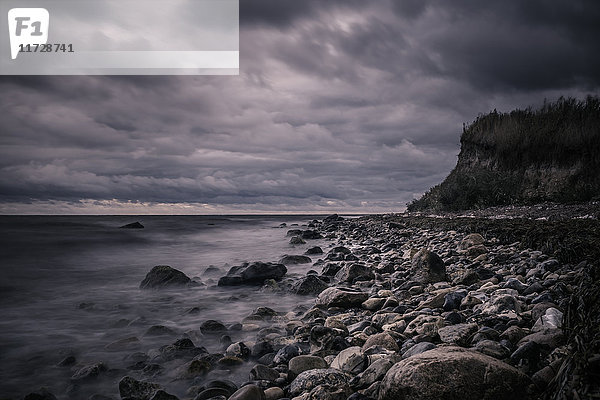 Ruhige Felsen am Meeresstrand unter stürmischen,  bedeckten Wolken,  Bisserup,  Dänemark