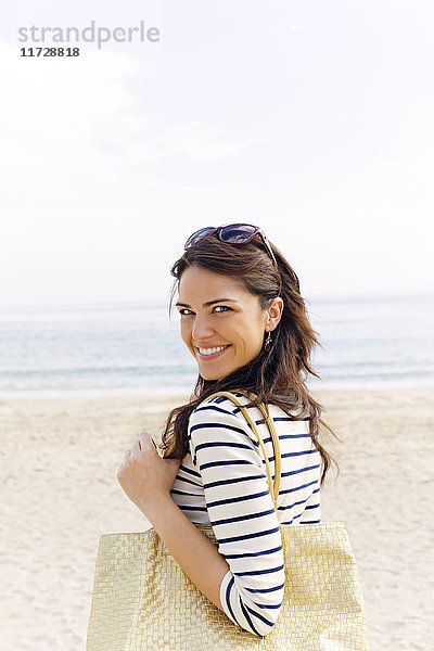 Porträt einer jungen brünetten Frau,  die am Strand ankommt