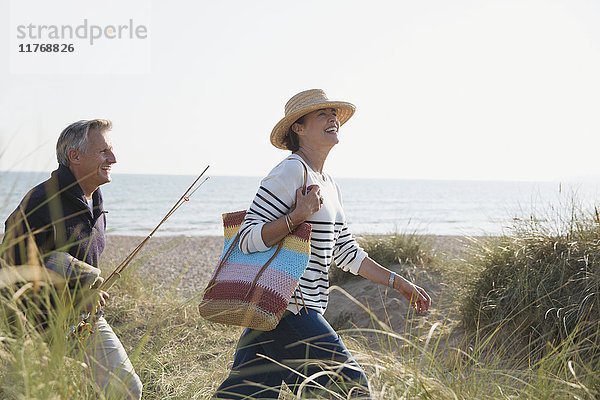 Erwachsenes Paar mit Angelrute im sonnigen Strandgras