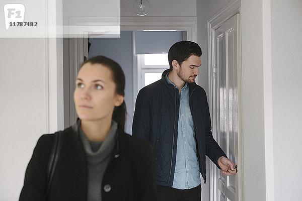Junger Mann schaut auf die Tür,  während er mit einer Frau im Flur steht.