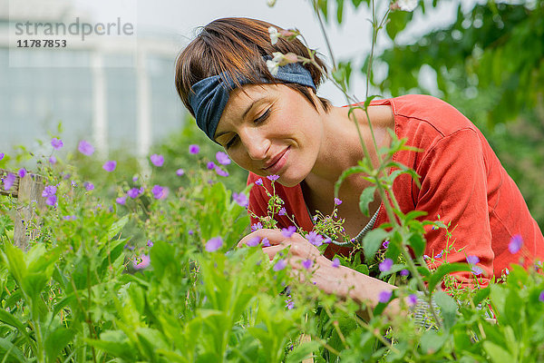 Frau riecht Blumen im Garten