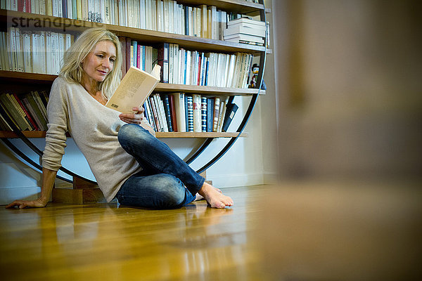 Reife Frau entspannt mit Buch zu Hause