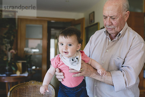 Happy Baby Mädchen stehend mit Hilfe von Urgroßvater zu Hause