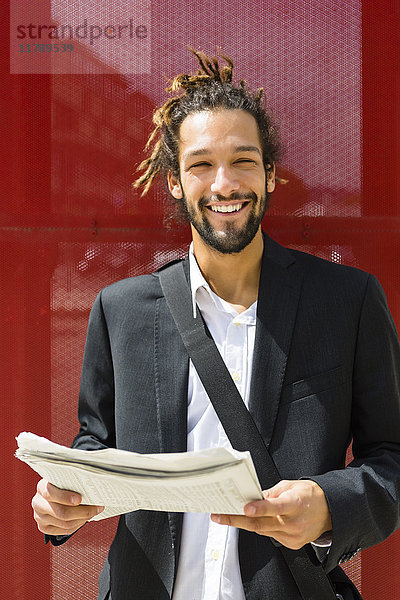 Portrait eines jungen Geschäftsmannes mit Dreadlocks beim Zeitungslesen