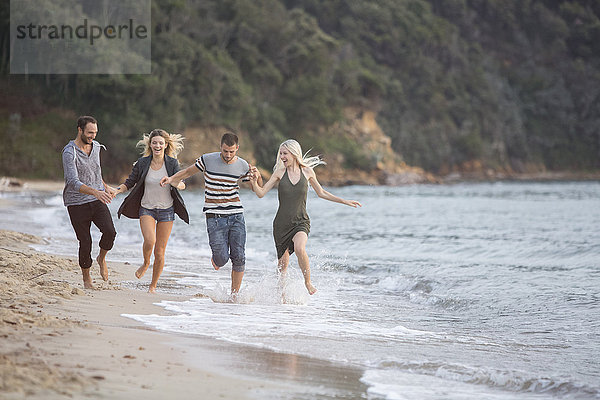 Vier glückliche Freunde beim Laufen am Strand