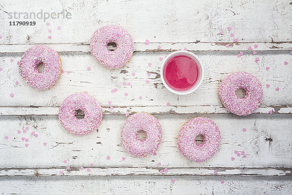 Sechs Donuts mit rosa Glasur und Zuckergranulat auf Holz