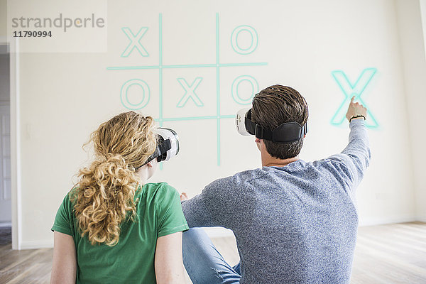 Junges Paar mit VR-Brille beim virtuellen Tic Tac Toe spielen