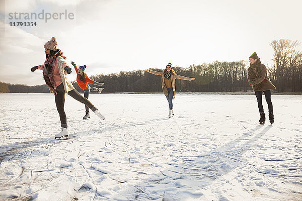 Glückliche Freunde Eislaufen auf dem zugefrorenen See