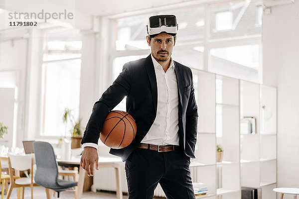Geschäftsmann mit VR-Brille hält Basketball im Amt