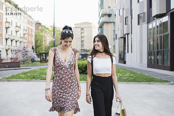 Zwei glückliche junge Frauen,  die in der Stadt spazieren gehen.