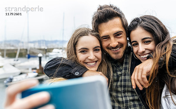 Drei Freunde,  die einen Selfie am Yachthafen nehmen.