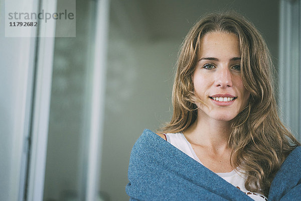Porträt einer lächelnden jungen Frau in eine Decke gehüllt