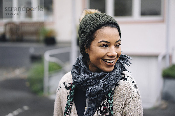 Lächelnde junge Frau mit Wollmütze im Freien
