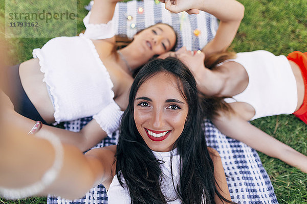 Selfie von Freunden im Park auf der Decke liegend