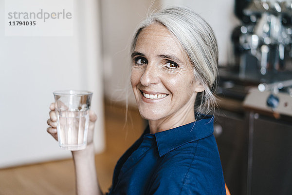 Porträt einer lächelnden Geschäftsfrau mit Wasserglas