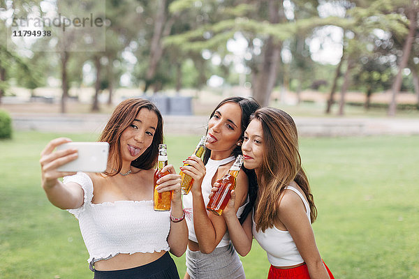 Verspielte Freunde im Park,  die Bier trinken und einen Selfie nehmen