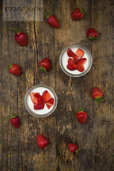 Zwei Gläser griechischer Joghurt mit Erdbeeren auf Holz