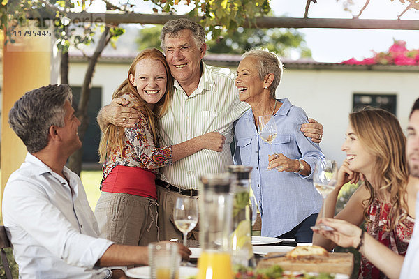 Fröhliches Seniorenpaar mit Familie beim gemeinsamen Mittagessen im Freien
