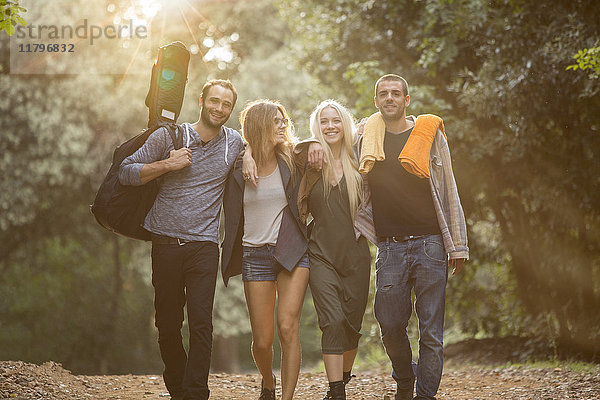Vier glückliche Freunde,  die im Wald spazieren gehen.