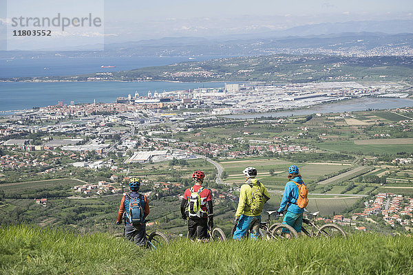 Mountainbiker blicken vom Berg aus auf Stadtbild und Meer