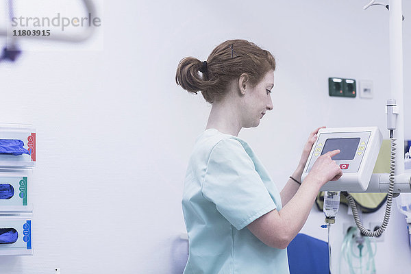 Weibliche Krankenschwester,  die medizinische Geräte bedient