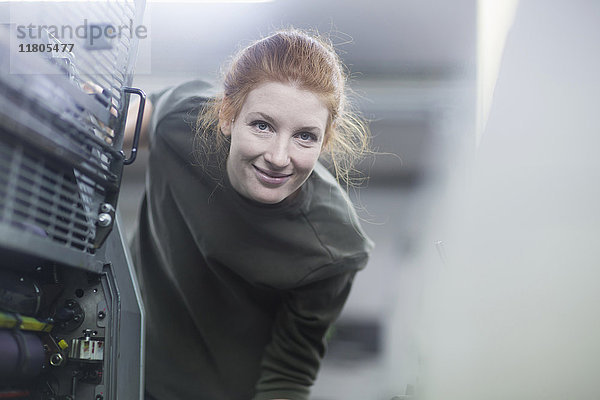 Porträt einer schönen Arbeiterin,  die an einer Druckmaschine steht