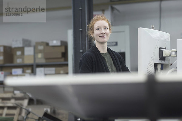 Lächelnder Druckereiarbeiter bei der Arbeit an einer Druckmaschine