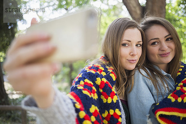Zärtliche weibliche Freunde,  die Selfie durch Smartphone im Park nehmen
