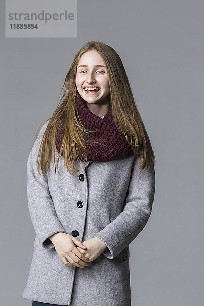 Porträt eines fröhlichen Teenagermädchens vor grauem Hintergrund