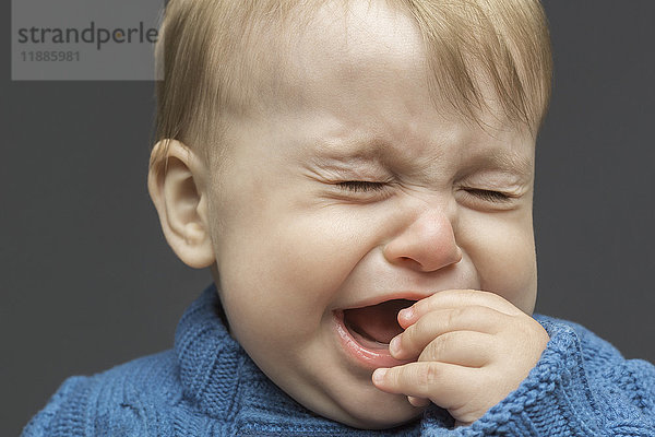 Nahaufnahme des weinenden Kleinkindes vor grauem Hintergrund