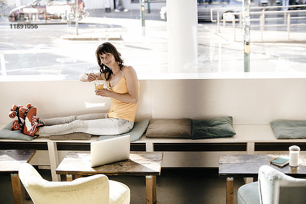 Frau mit Rollschuhen in einem Café sitzend,  einen Drink nehmend