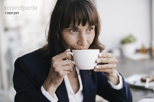Geschäftsfrau sitzend im Café,  Kaffee trinkend