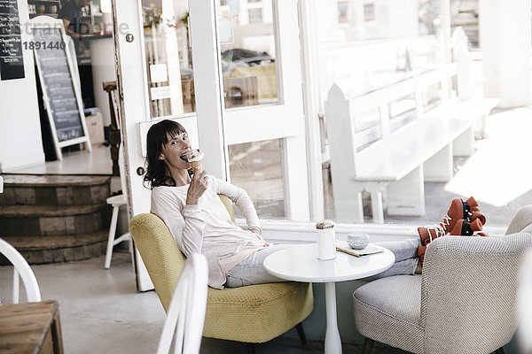 Frau mit Rollschuhen in einem Café sitzend,  Eis essend