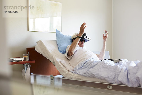 Senior Mann mit VR-Brille auf dem Bett in der Krankenstation