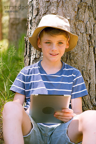Junge mit digitalem Tablett im Wald