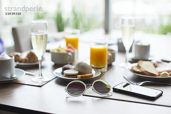 Sonnenbrille und Frühstück auf dem Tisch im Cafe