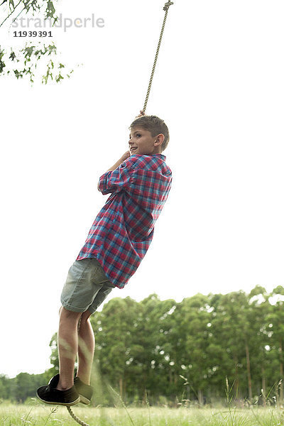 Junge schwingt am Seil im Freien
