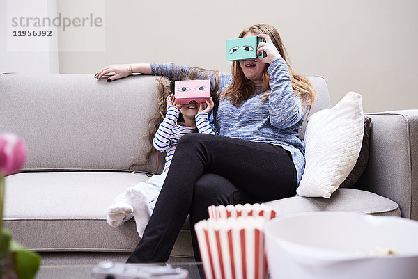 Mutter und Tochter sitzen auf der Couch und haben Spaß mit der Virtual Reality Brille.