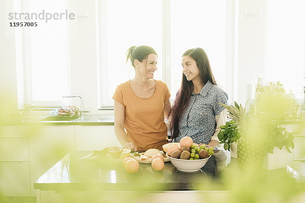 Zwei lächelnde Frauen in der Küche beim Zubereiten von Obst