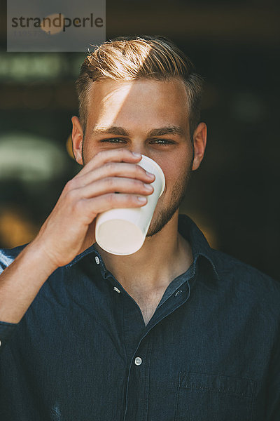 Portrait eines jungen Mannes mit Kaffee zum Mitnehmen