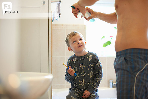 Junge im Badezimmer mit Vater,  der sich zum Zähneputzen vorbereitet