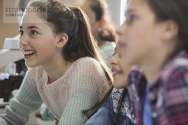 Neugierige,  lächelnde Mädchen,  die im Klassenzimmer zuhören.