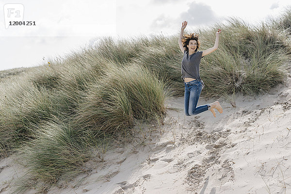 Glückliche Frau beim Springen in der Stranddüne
