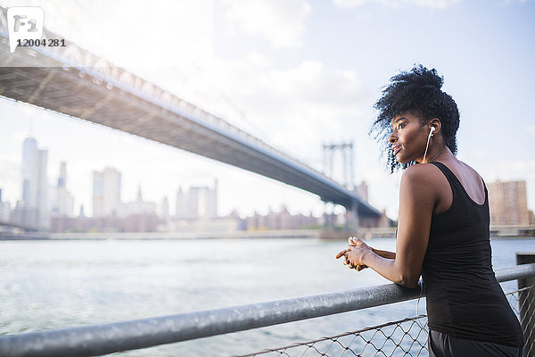USA,  New York City,  Brooklyn,  Frau hört Musik in der Nähe von Manhattan Bridge