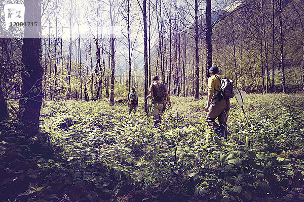 Slowenien,  Bovec,  drei Angler,  die im Wald Richtung Soca-Fluss wandern