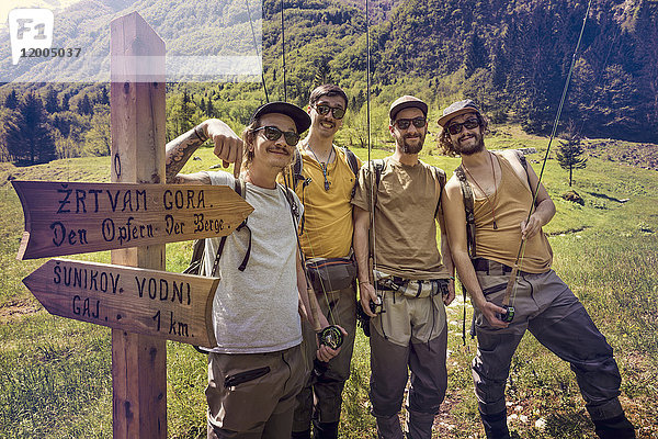Slowenien,  Bovec,  vier Angler posieren am Wegweiser auf der Wiese am Fluss Soca