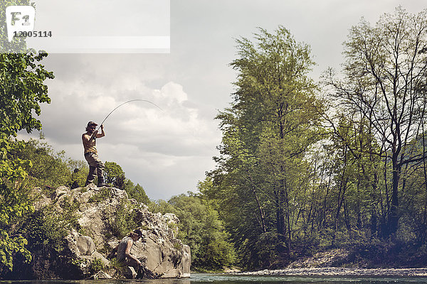 Slowenien,  Mann Fliegenfischen im Fluss Soca auf einem Felsen stehend
